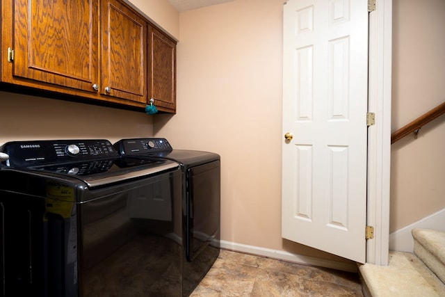 clothes washing area featuring washer and clothes dryer and cabinets