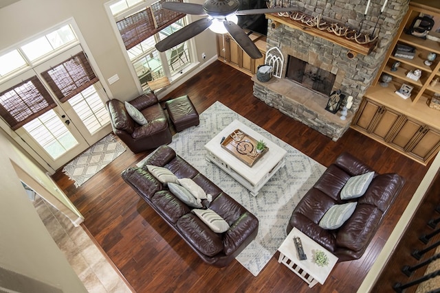 living area featuring a ceiling fan, a stone fireplace, hardwood / wood-style flooring, and a healthy amount of sunlight