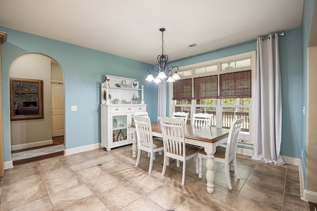 dining room featuring arched walkways, visible vents, baseboards, and a notable chandelier