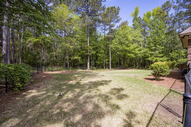 view of yard with a wooded view and fence