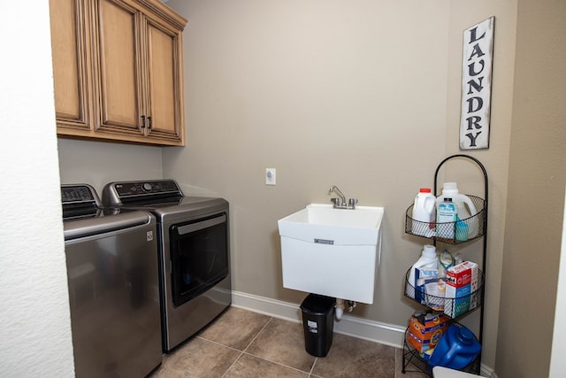 laundry room with a sink, baseboards, washer and dryer, dark tile patterned flooring, and cabinet space