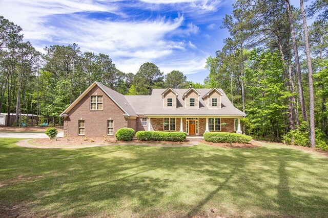 cape cod-style house featuring a front lawn, brick siding, and covered porch