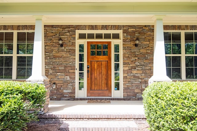 view of exterior entry with a porch and stone siding