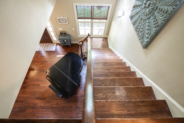 stairs featuring a textured wall, baseboards, and wood finished floors