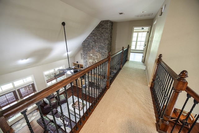 hallway featuring lofted ceiling, an upstairs landing, and visible vents