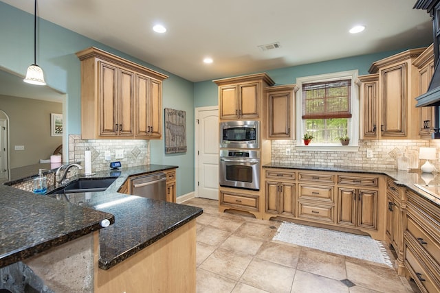kitchen with stainless steel appliances, a sink, dark stone counters, backsplash, and brown cabinetry