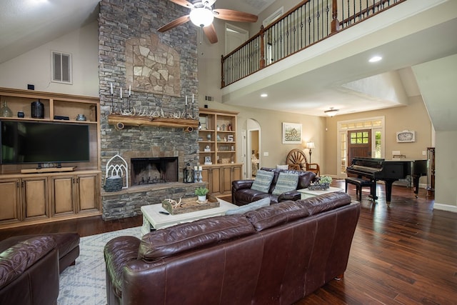 living room with dark wood-style floors, arched walkways, ceiling fan, and visible vents
