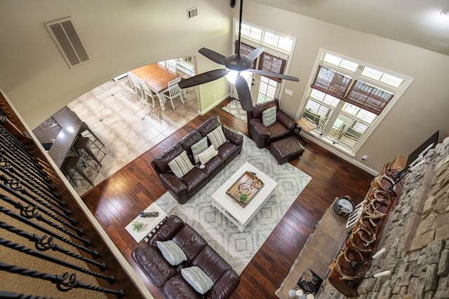 living area featuring baseboards, hardwood / wood-style flooring, visible vents, and ceiling fan
