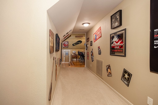 corridor featuring vaulted ceiling, visible vents, and carpet flooring