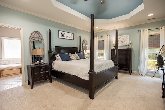 bedroom featuring light carpet, a tray ceiling, visible vents, baseboards, and ornamental molding