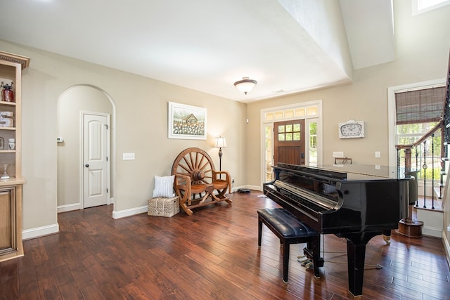 sitting room featuring arched walkways, dark wood-style floors, and baseboards