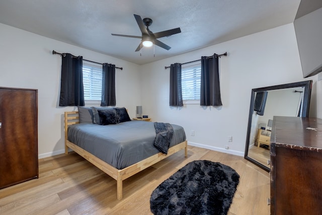 bedroom featuring ceiling fan, light hardwood / wood-style flooring, and a textured ceiling