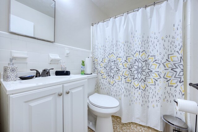 bathroom featuring tile walls, vanity, and toilet