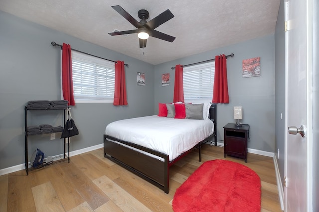 bedroom with ceiling fan, a textured ceiling, and light wood-type flooring