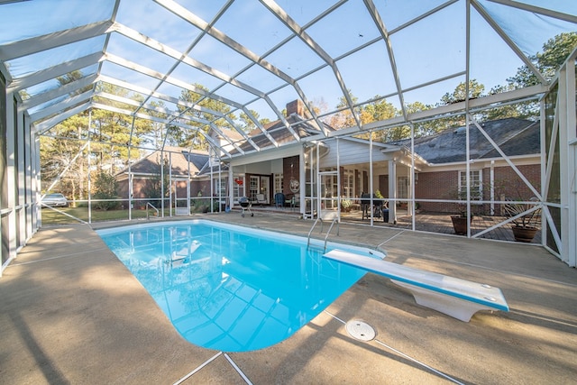 view of pool with a patio area, a diving board, and glass enclosure