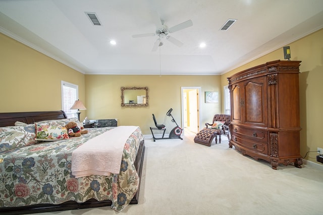 bedroom with ceiling fan, light colored carpet, crown molding, and a tray ceiling