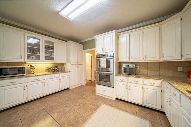 kitchen with white cabinets, backsplash, stainless steel appliances, and crown molding