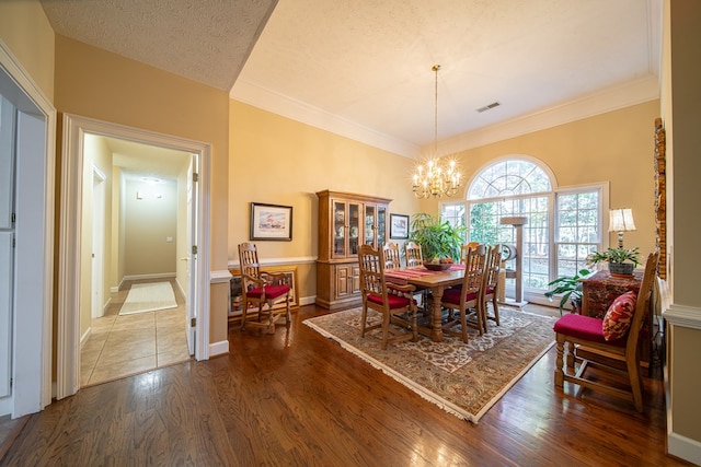 dining room with crown molding, dark wood-type flooring, a textured ceiling, and a notable chandelier