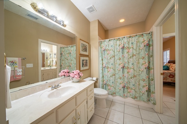 bathroom featuring tile patterned floors, vanity, a textured ceiling, and toilet