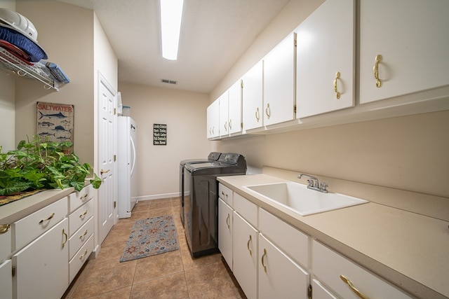 laundry room featuring sink, light tile patterned floors, cabinets, and independent washer and dryer