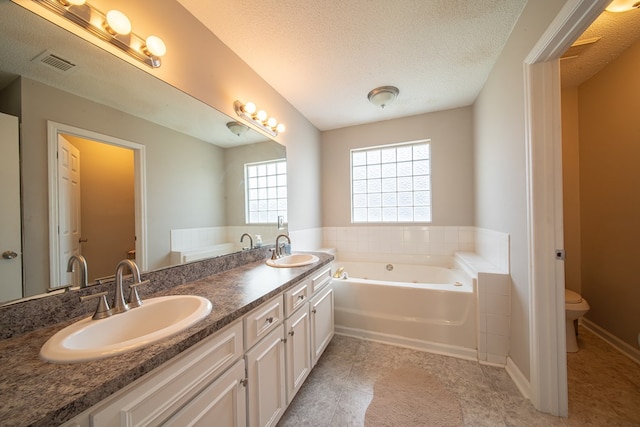 bathroom featuring tile patterned floors, vanity, a textured ceiling, toilet, and a bathing tub