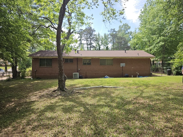 rear view of house featuring brick siding, a yard, central air condition unit, and fence