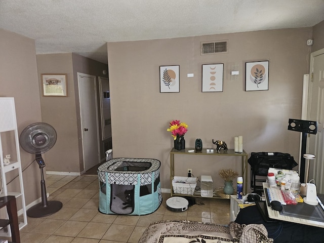 interior space featuring light tile patterned flooring, a textured ceiling, visible vents, and baseboards