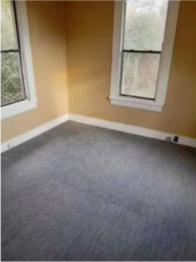 spare room with dark colored carpet