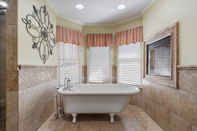 full bath with a freestanding tub, a textured ceiling, tile walls, and ornamental molding