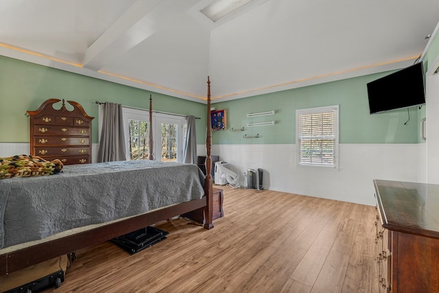 bedroom featuring multiple windows, wood finished floors, and wainscoting