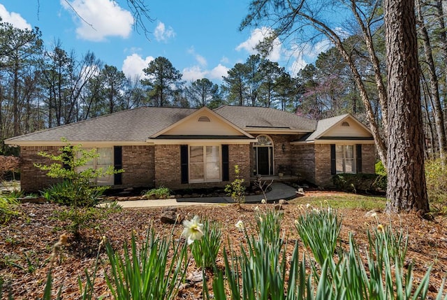 ranch-style home featuring brick siding and a shingled roof