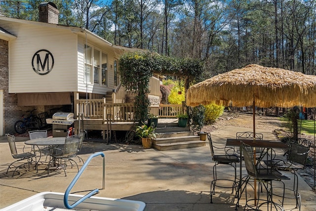 view of patio / terrace featuring outdoor dining space, a wooden deck, and grilling area