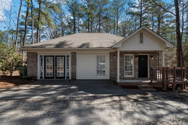 view of front facade with french doors, brick siding, and roof with shingles