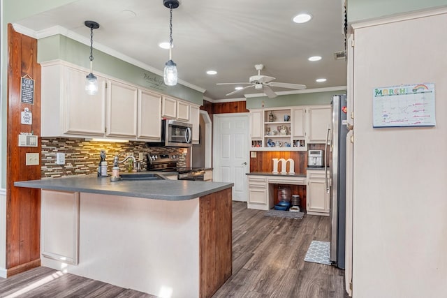 kitchen with a sink, ornamental molding, appliances with stainless steel finishes, a peninsula, and dark wood-style flooring