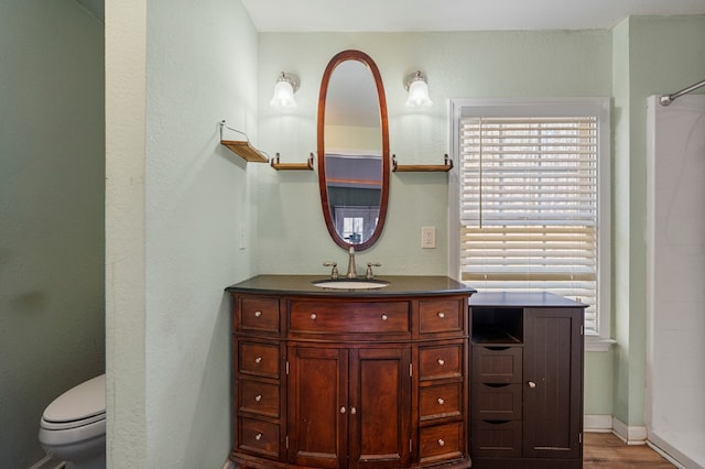 full bathroom with vanity, wood finished floors, baseboards, a shower, and toilet