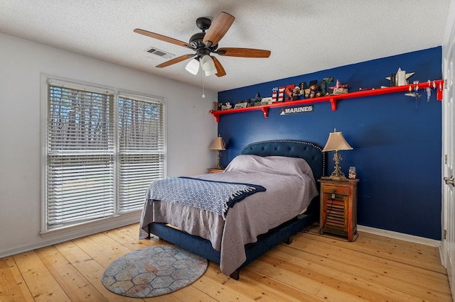 bedroom featuring hardwood / wood-style floors, baseboards, visible vents, and a textured ceiling