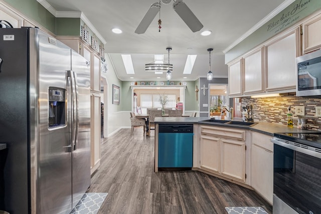 kitchen featuring a peninsula, a sink, dark wood-type flooring, appliances with stainless steel finishes, and crown molding