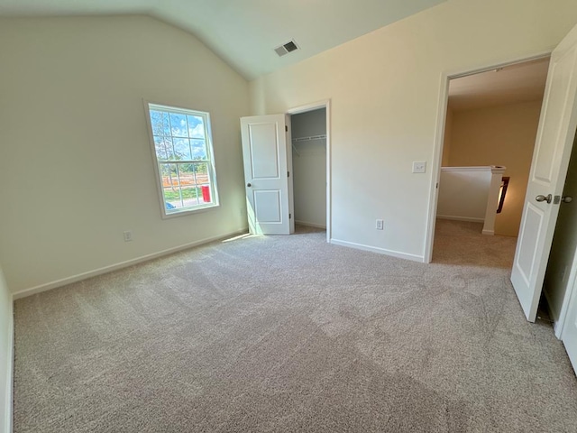 unfurnished bedroom with light colored carpet, lofted ceiling, and a closet