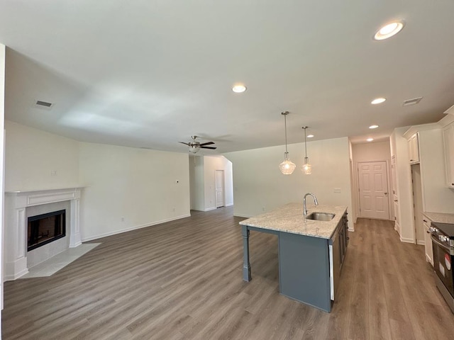 kitchen with white cabinetry, sink, hardwood / wood-style floors, an island with sink, and decorative light fixtures