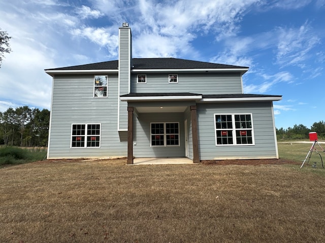 rear view of property with a patio and a lawn