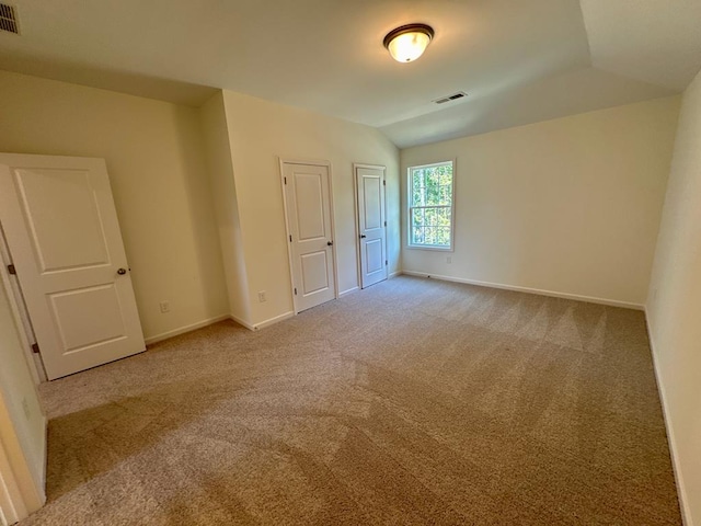 empty room with light carpet and vaulted ceiling