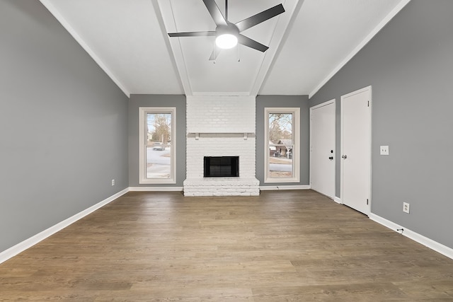 unfurnished living room featuring ceiling fan, crown molding, wood-type flooring, vaulted ceiling, and a fireplace