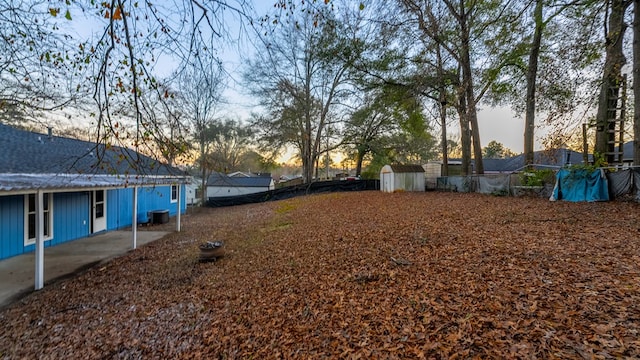 yard at dusk featuring cooling unit and a storage shed