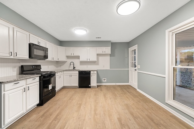 kitchen with light stone countertops, sink, white cabinetry, and black appliances