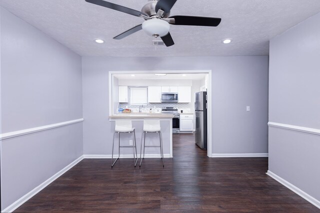 kitchen with a breakfast bar area, stainless steel appliances, white cabinets, and a kitchen island