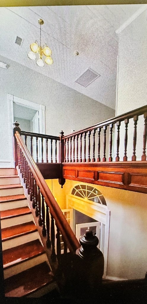 staircase with a notable chandelier