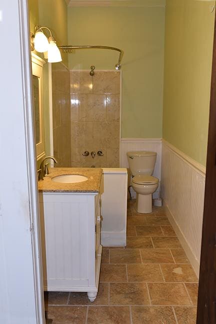 bathroom with a tile shower, vanity, and toilet