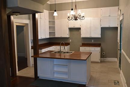 kitchen featuring wood counters, sink, pendant lighting, a notable chandelier, and white cabinetry