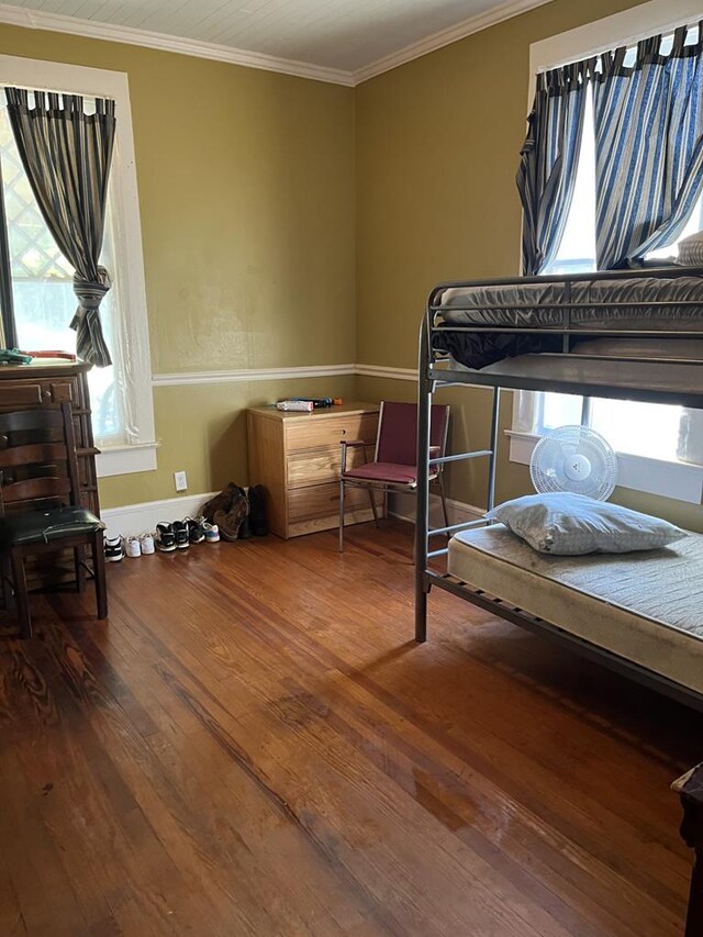 bedroom featuring wood-type flooring, multiple windows, and crown molding