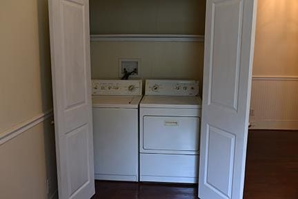 clothes washing area with dark hardwood / wood-style flooring and washing machine and clothes dryer